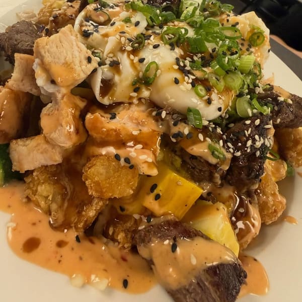 A breakfast bowl with a poached egg, steak, sesame and scallions